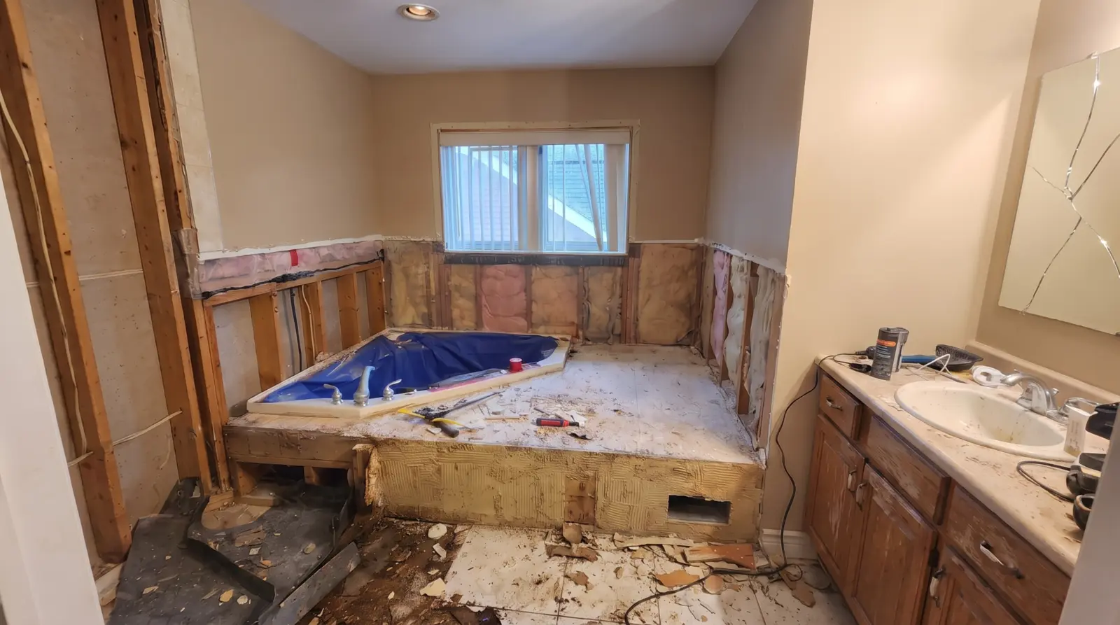 Ensuite bathroom stripped to the studs with the corner tub deck exposed before renovation